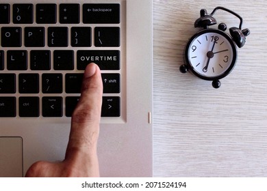 Overtime work concept. Finger pressing keyboard with text OVERTIME and black alarm clock. - Shutterstock ID 2071524194