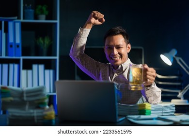 Overtime work concept, Handsome asian business man looking football league on laptop with beer glass, soccer fans. - Shutterstock ID 2233561595