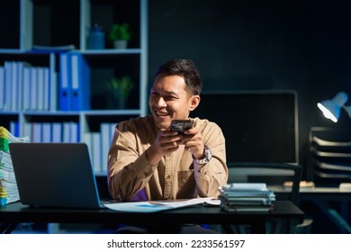 Overtime work concept, Handsome asian business man working late at night in office workplace. - Shutterstock ID 2233561597
