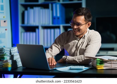 Overtime work concept, Handsome asian business man working late at night in office workplace. - Shutterstock ID 2233561623