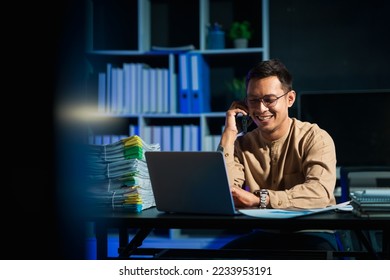 Overtime work concept, Handsome asian business man working late at night in office workplace. Mobile calling. - Powered by Shutterstock