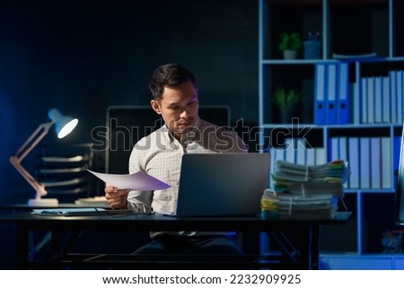 Overtime work concept, Handsome asian business man working late at night in office workplace.