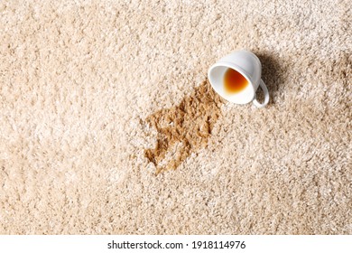 Overturned cup and spilled tea on beige carpet, top view. Space for text