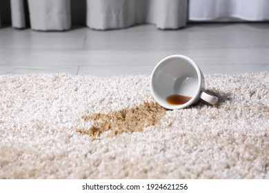 Overturned cup and spilled tea on beige carpet, closeup. Space for text