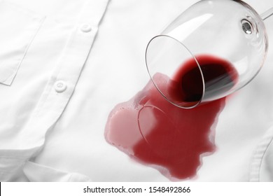 Overturned glass and spilled exquisite red wine on white shirt. Space for text