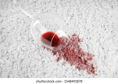Overturned glass and spilled exquisite red wine on soft carpet