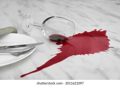 Overturned Glass And Spilled Red Wine On White Marble Table