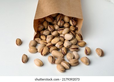 Overturned Paper Bag With Pistachio Nuts On White Background