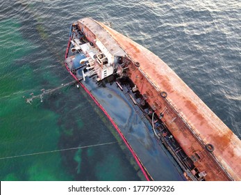 An overturned rusty tanker ran aground. Environmental disaster and oil spill into the sea by the sea. Old ship on the background of the emerald sea.