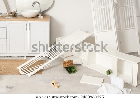 Overturned shelf unit with folding screen in messy bathroom
