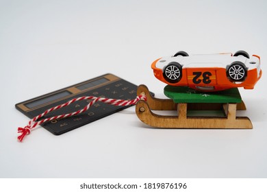 An Overturned Toy Car Lies On A Sled, Near A Calculator, A Symbol Of Auto Insurance And New Year's Discounts