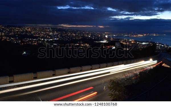 Overview of Beirut at dusk while\
lights are on, with tracks on cars lights on motion on\
foreground
