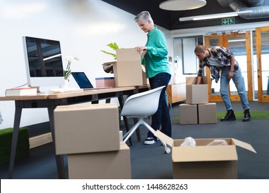 Overview of diverse male and female executives unpacking cardboard boxes in new office. This is a casual creative start-up business office for a diverse team - Powered by Shutterstock