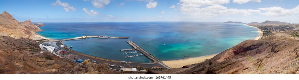 Overview Of Porto Santo Bay, Beach And Harbour. Blue And Green Waters Under A Clouded Blue Sky. A Ship Is Docked And Vila Baleira Can Be Seen To The Right. Madeira, Portugal.