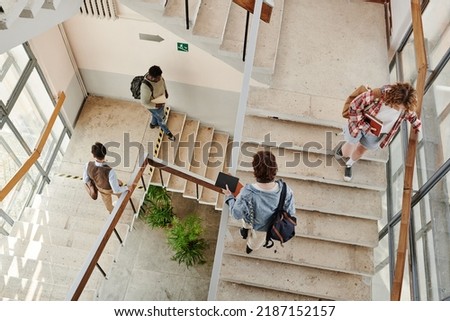 Overview of teenage students going up and down staircase in corridor while leaving for home or another university building
