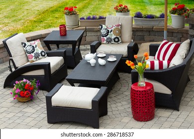 Overview Of Upscale Patio Set, Dark Wicker Luxury Furniture With Comfortable Cushions On Outdoor Stone Patio Of Affluent Home