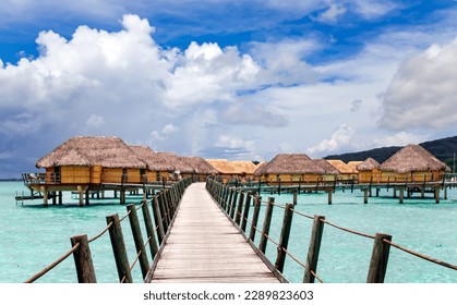 Overwater bungalows stretching and a wooden bridge out across the lagoon in Bora Bora island, Tahiti. Romantic honeymoon destination. - Powered by Shutterstock