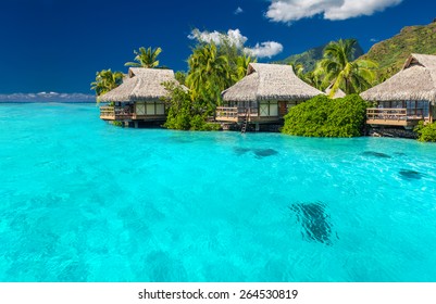 Overwater villas in tropical lagoon of Moorea Island with coral reef