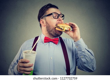 Overweight Business Man Eating With Appetite A Burger Holding A Big Can Of Soda Drink 