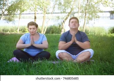 Overweight couple training together on green grass