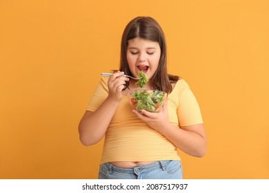 Overweight girl eating healthy vegetable salad on color background