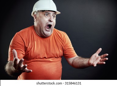 Overweight industrial supervisor gesturing disappointed. All over black background.