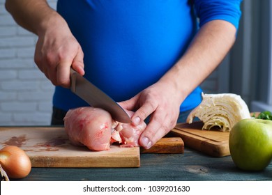 Overweight Man Cooking Diet Food. Plus-size Guy Chopping Chicken Breasts Preparing Low-calorie Meals. Weight Losing, Dieting And Healthy Lifestyle