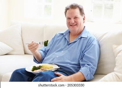 Overweight Man Eating Healthy Meal Sitting On Sofa