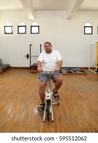 Overweight Man Exercising On Bike Simulator