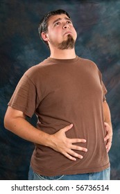 Overweight man holds his stomach after eating too much resulting in indigestion.