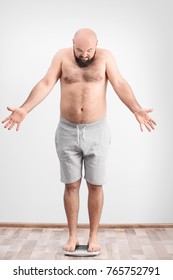 Overweight Man Measuring His Weight Using Scales On Floor