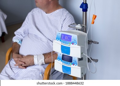 Overweight Man Sitting In A Chair With A Dropper, Equipment In The Foreground, Patient In Hospital