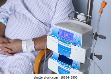 Overweight Man Sitting In A Chair With A Dropper, Equipment In The Foreground, Patient In Hospital