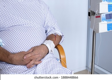 Overweight Man Sitting In A Chair With A Dropper, Equipment In The Foreground, Patient In Hospital