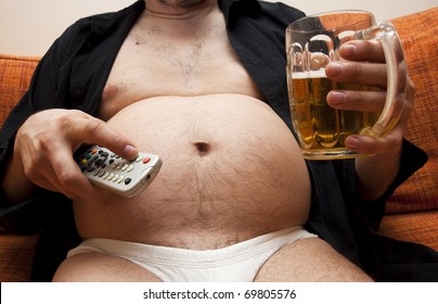 Overweight man sitting on the couch with a beer glass and remote control