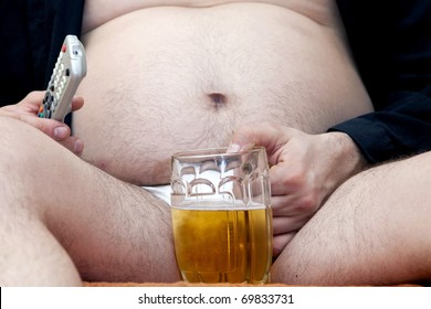 Overweight man sitting on the couch with a beer glass and remote control