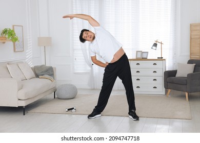 Overweight Man Stretching Near Sofa In Living Room