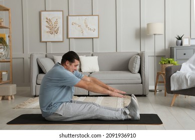 Overweight Man Stretching On Mat At Home