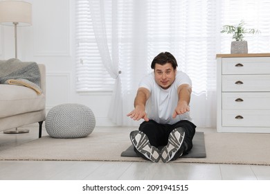 Overweight Man Stretching On Mat At Home, Space For Text