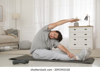 Overweight Man Stretching On Mat At Home