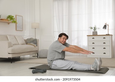 Overweight Man Stretching On Mat At Home, Space For Text