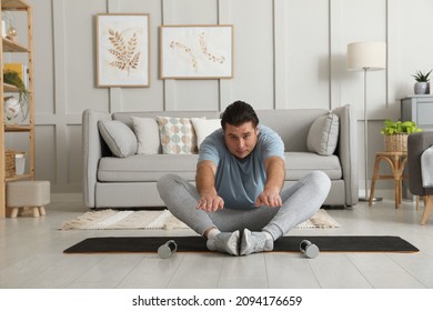 Overweight Man Stretching On Mat At Home