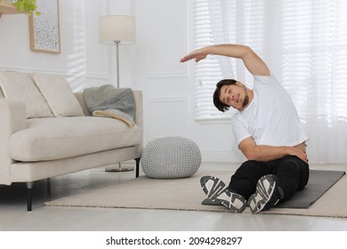 Overweight Man Stretching On Mat At Home, Space For Text