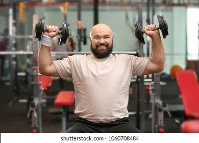 Overweight Man Training With Dumbbells In Gym