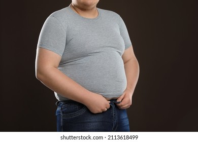 Overweight Man Trying To Button Up Tight Jeans On Dark Brown Background, Closeup