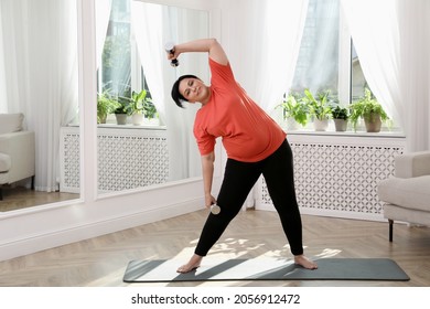 Overweight Mature Woman Doing Exercise With Dumbbells At Home