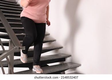 Overweight mature woman running downstairs indoors, closeup. Space for text
