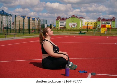 Overweight Obese Chubby Woman Doing Breathing Exercises In Sports Ground Before Training. Yoga Pose For Relaxation And Meditation. Summer Time For Fitness And Outdoor Sports In The Fresh Air