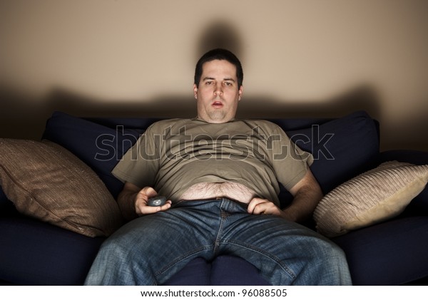 Overweight slob\
watches TV with belly\
showing