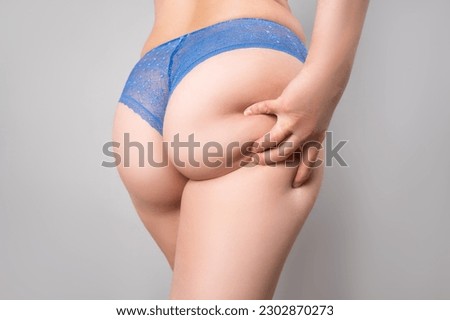 Overweight thigh, woman with fat hips and buttocks, obesity female body with cellulite on gray background, studio shot